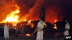 Pakistani paramilitary soldiers stand guard as trucks and tankers carrying supplies bound for NATO forces in Afghanistan burn following the overnight attack in Shikarpur.