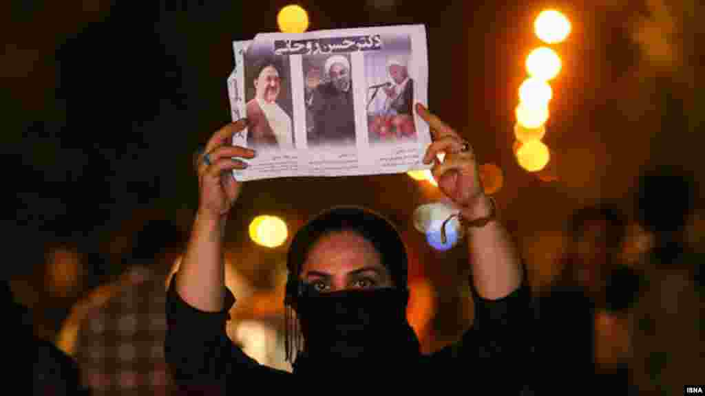 A woman displays images of pro-reform leaders who have allied themselves behind the candidacy of Hassan Rohani.