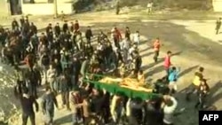 Syrian mourners carrying the coffin of a woman who was reportedly killed in the Hula region of central Homs province on December 12.