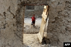 An Internally displaced Afghan child looks out from within his temporary home at a refugee camp in Kabul in December.