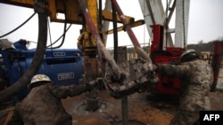 Workers connect 30-foot sections of steel pipe at a well site in the Barnett Shale field near Fort Worth, Texas.