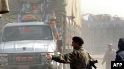 Pakistani police guard trucks carrying NATO supplies crossing a street in Jamrud, Pakistan, earlier this month.