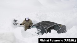 A man attempts to dig his car out of heavy snow in the Bosnia capital, Sarajevo.