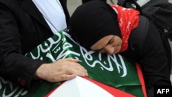 The wife of one of the nine activists killed in the Israeli raid on the Gaza aid convoy weeps on his coffin.