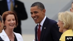 U.S. President Barack Obama (center) is greeted by Australian Prime Minister Julia Gillard (left) upon his arrival in Canberra on November 16.