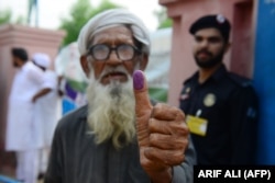 An elderly Pakistani man shows his inked thumb after casting his vote outside a polling station during general elections in Lahore.