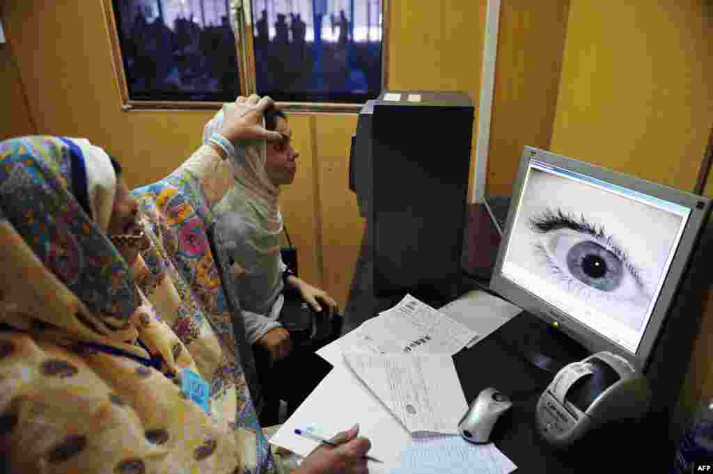 A UNHCR employee scans the eye of an Afghan at a refugee registration center outside Peshawar, Pakistan in June 2011.