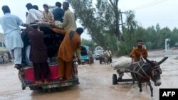 Pakistani people cross a flooded street in Peshawar on August 3. 