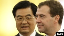 Chinese President Hu Jintao (left, with Russian President Dmitry Medvedev, abruptly changed plans amid scenes of prowling groups of armed men in Xinjiang.