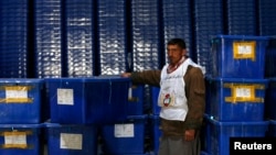 An Afghan Election Commission worker stands by ballot boxes and election material at a warehouse in Kabul. Turnout is expected to be much higher than in 2009.