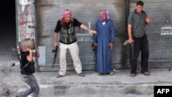 A Syrian rebel carries a homemade explosive device as others stand back to let him pass during fighting in Aleppo, which could have a crucial impact on the course of events in Syria. 