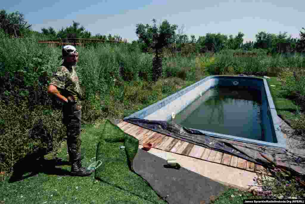 A soldier nicknamed Wolf checks out a dirty swimming pool at a mansion in Pisky.