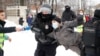 A man wearing a press vest holds a microphone as police detain a protester during a rally in support of jailed Russian opposition leader Aleksei Navalny in St. Petersburg on January 31.