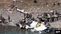 Tajik National Guard soldiers gather around the debris of a Mi-8 helicopter that crashed in the mountainous Rasht Valley on October 6. Some reports say the helicopter was brought down in a militant attack.