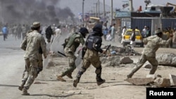 Afghan riot police run toward protesters during a demonstration in Kabul on September 17.