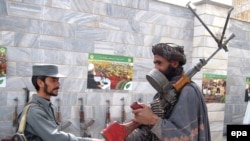 A former Taliban fighter (right) shakes hands with a policemen in Herat as he and other militants attend a ceremony to surrender under a U.S.-backed Afghan government amnesty scheme.