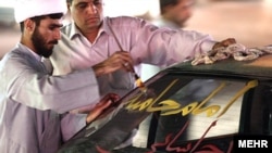 A man writes pro-Khamenei slogans on the windshield of a car in Qom ahead of the supreme leader's visit.