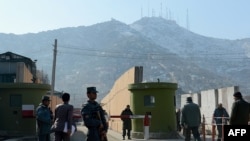 Afghan policemen stand guard at the entrance to police headquarters on December 24 in Kabul where a female police officer shot dead a foreign civilian adviser.