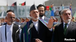 Afghan President Hamid Karzai (center) speaks during celebrations to commemorate Afghanistan's 95th anniversary of independence as he is flanked by presidential candidates Abdullah Abdullah (right) and Ashraf Ghani in Kabul on August 19.