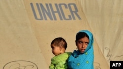 An internally displaced girl carries a child at a makeshift tent camp in Swabi on May 25.