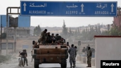 Turkey-backed Syrian rebel fighters sit on a military truck at the border town of Tel Abyad on October 14.