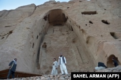 Taliban militants stand guard in front of the site where the Shahmama Buddha statue once stood before being destroyed by the Taliban in March 2001 in the central Bamiyan Province.