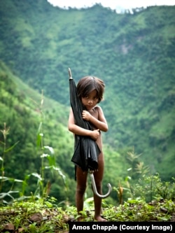 A small girl clutches an umbrella on a chilly day in the highlands of Nepal. Photo by Amos Chapple