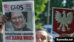 A supporter of Andrzej Poczobut holds a newspaper with his portrait in front of the court building in Hrodna on June 28