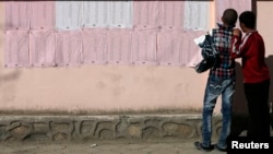 Afghan boys look on a preliminary list taped to the wall of a polling station in Kabul on April 7.