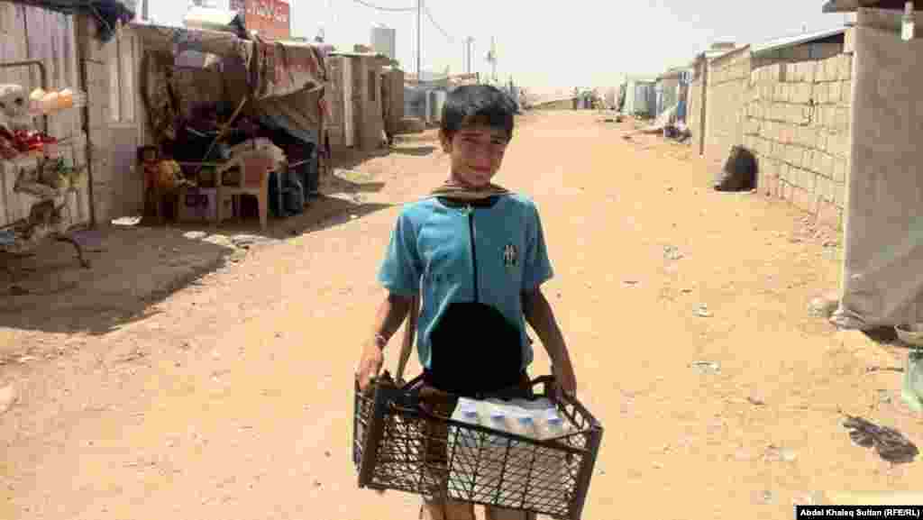 Part of an earlier wave of refugees, a child carries supplies at the Domeez refugee camp in Iraq&#39;s Duhok Province on July 4.