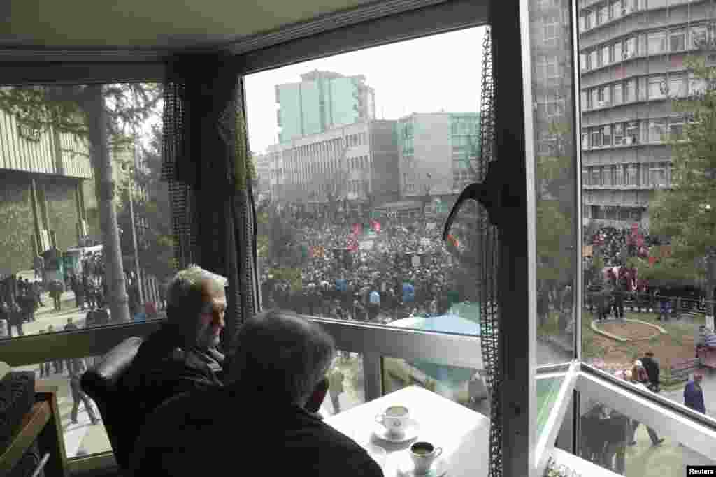 People at a cafe watch a protest organized by the opposition movement Vetevendosje (Self-Determination) in Mitrovica on March 20. Thousands marched to protest against the planned talks between Kosovo and Serbia.