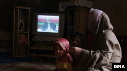 An Iranian woman and her child watch one of the three televised presidential debates in early June.