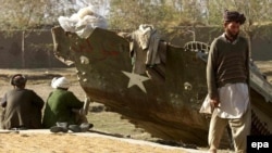 Afghans dry rice on a road in front of a broken old Soviet personnel carrier in northern Afganistan in November 2001.