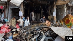 Pakistani merchants gather beside their damaged shops in Peshawar on September 30, the day after a bomb blast.