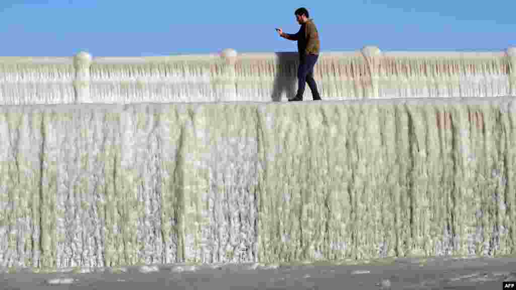 A man takes pictures of frozen seawater on a wall covered with ice in Constanta, Romania.