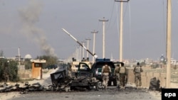 Members of the Afghan security forces walk past the wreck of a burnt-out vehicle en route to the center of Kunduz on October 1. 