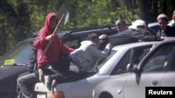 Rioters ride on top of a car during unrest in the village of Mayevka, near Bishkek, today.