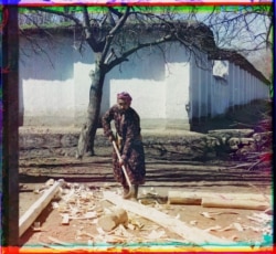 A carpenter strips bark from fresh timber on a back road in Samarkand.