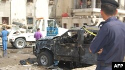 A police officer looks at the scene of a deadly suicide attack in front of a police station in Basra on June 13.