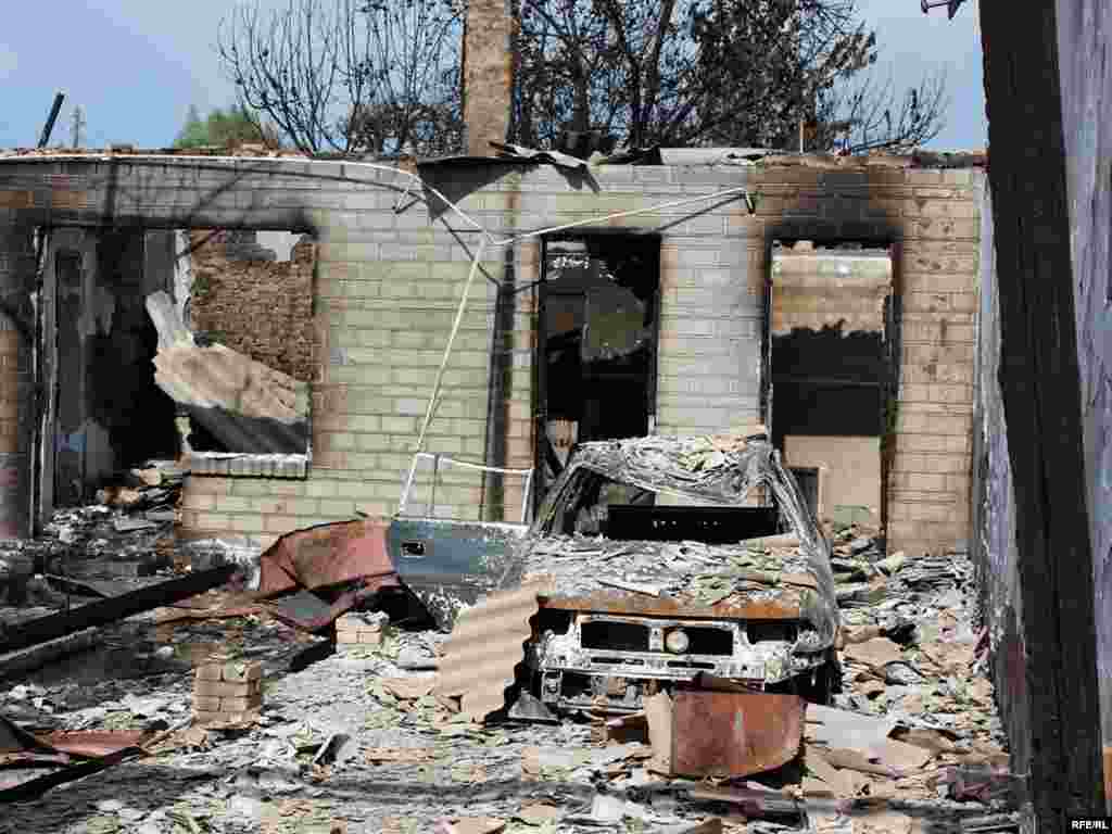 Burned-out buildings and a vehicle in the ethnic Uzbek Cheremushky neighborhood of Osh -  