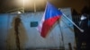 A protester holds a Czech national flag in front of the walls of the Russian Embassy in Prague on April 18. Protesters splashed ketchup on the walls of the embassy to call attention to the deaths of the two people in a 2014 arms depot explosion the Czechs now blame on Russian agents.