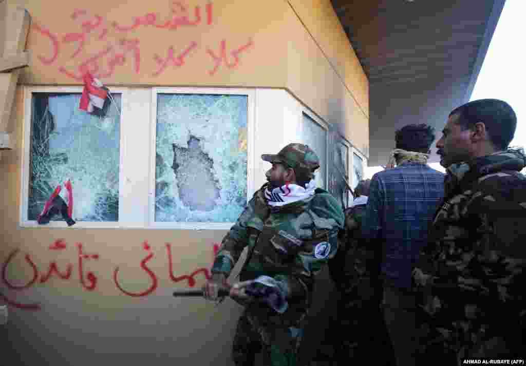 Members of an Iran-backed Shi&#39;ite militia smash the bulletproof glass of the U.S. Embassy in Baghdad on December 31, 2019. The U.S. military said that Soleimani &quot;approved the attack&quot; and had organized several other attacks on U.S.-led coalition bases in Iraq over the past several months.