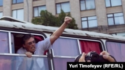 One of the detained protesters gestures to journalists and supporters from a police bus as he is taken from the rally in central Moscow on July 31.