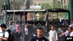 Egyptians walk past a burned-out armed forces bus at Tahrir Square in Cairo on April 9.