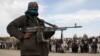 A Taliban fighter and viewers attend the execution of three men in Ghazni Province in 2015.