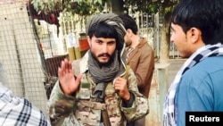 A Taliban fighter talks with residents in the main square after insurgents took control of the strategic northern city of Kunduz.