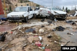 A child's doll lies in front of destroyed cars after flooding in the southern city of Shiraz.