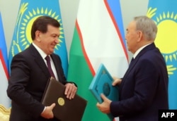 Kazakh President Nursultan Nazarbaev (right) and Shavkat Mirziyaev exchange documents during a signing ceremony following their meeting in Astana in March.