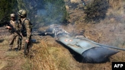 Pakistani soldiers stand next to the wreckage of an Indian fighter jet shot down in Pakistan-controlled Kashmir on February 27.