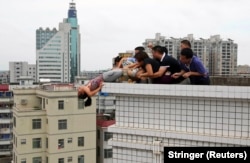 Rescuers and relatives grapple with a woman attempting to leap to her death in Zhanjiang, China, in 2012. They saved her. Photo by Reuters/Stringer